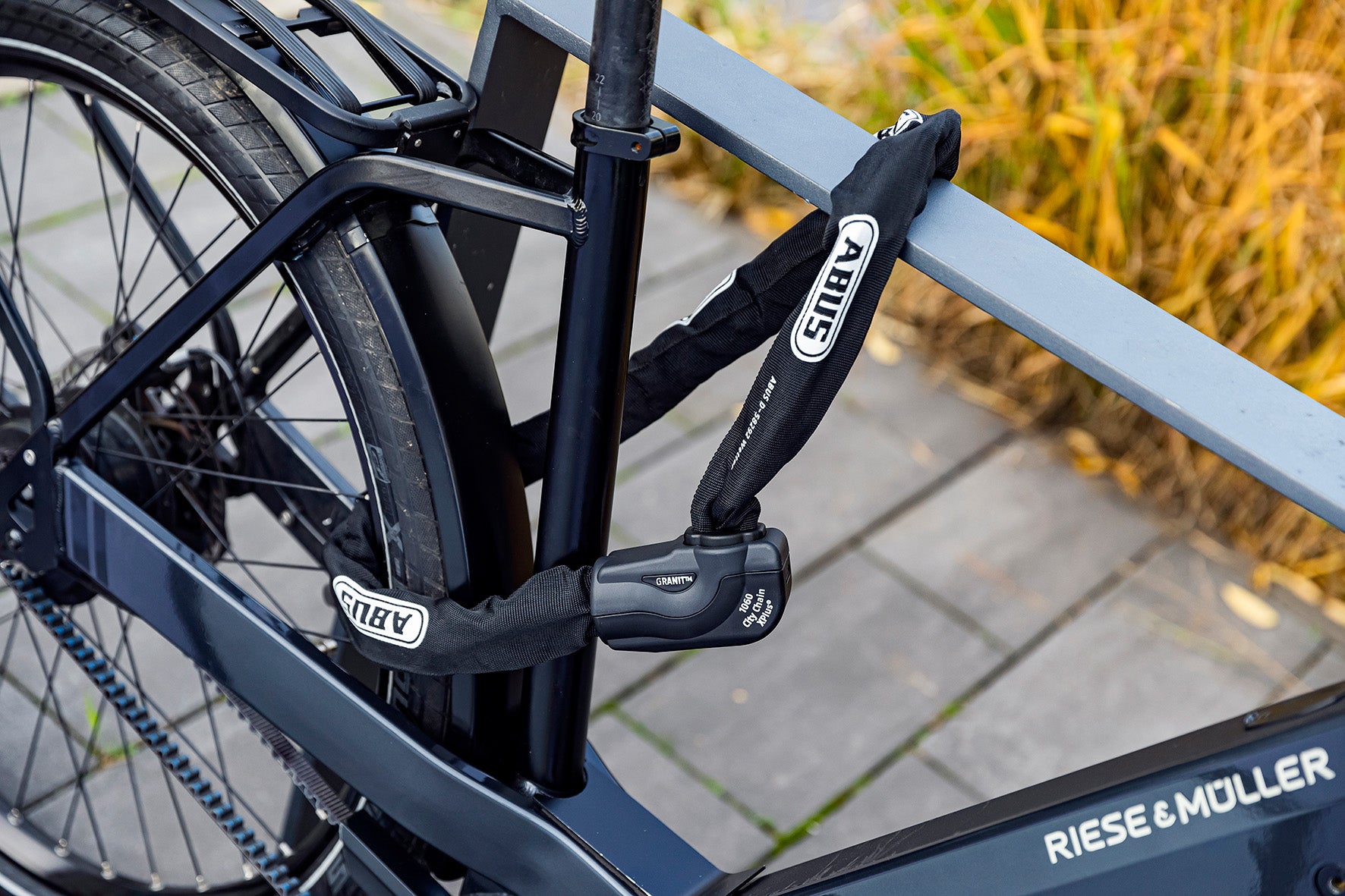 Riese & Müller Fahrrad mit Abus Kettenschloss Granit, gesichert an einem Geländer. Ideal für City-Trekking.