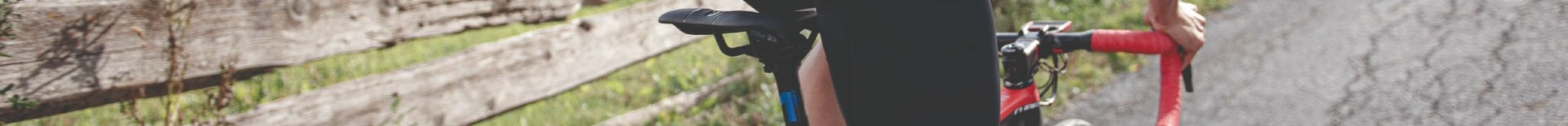 Fahrradfahrer auf einer Landstraße mit rotem Rennradlenker und schwarzem Sattel, Freizeit- oder Sporteinsatz im Freien.