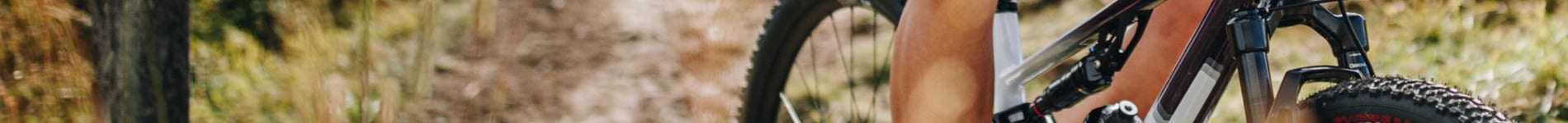 Teil eines BMC Mountainbikes im Wald, Fokus auf Reifen und Federung, geeignet für Offroad-Abenteuer.