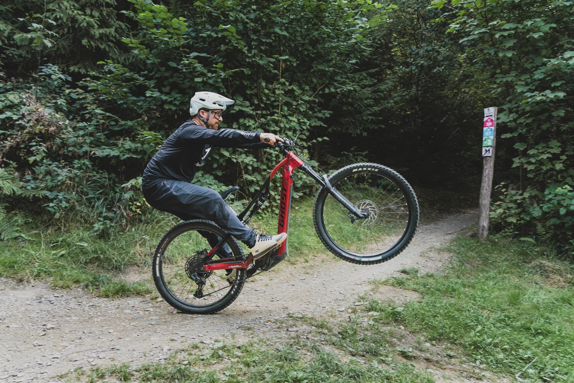 Marc Brodesser macht einen Wheelie mit einem Ghost E-MTB im Trailgorund Brilon