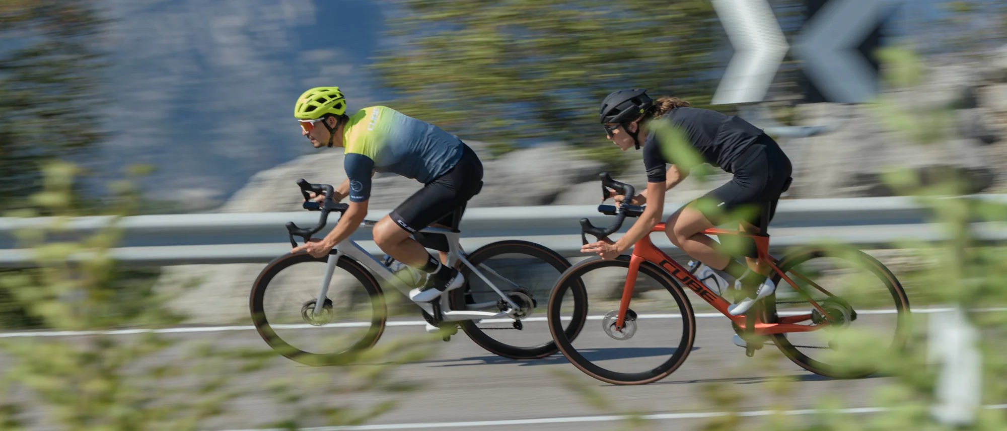 Zwei Radfahrer auf Cube-Rennrädern in Aktion auf einer Straße, einer trägt einen gelben Helm, der andere einen schwarzen.