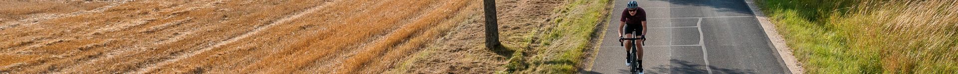 Radfahrer auf Landstraße neben Getreidefeld, Modell Cube Attain, ideal für Ausfahrten in der Natur.