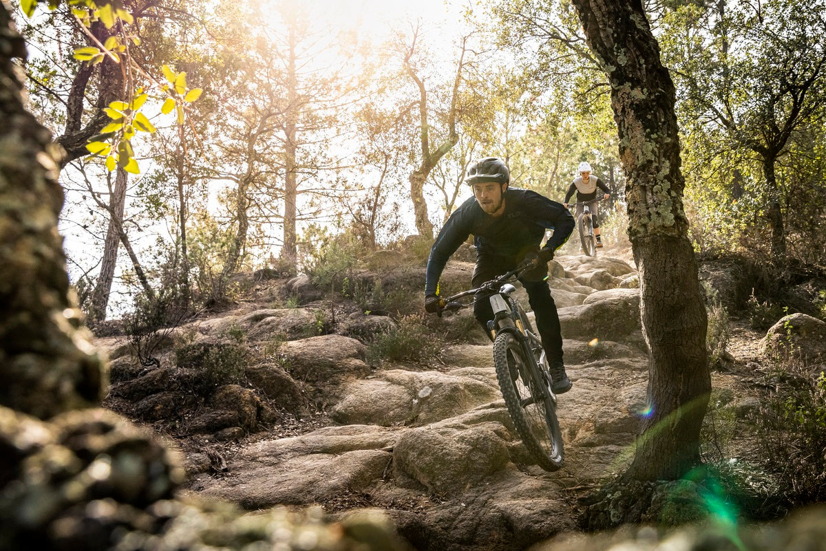 Zwei Mountainbiker fahren auf einem steinigen Waldweg bergab. Ideal für abenteuerliches Gelände.