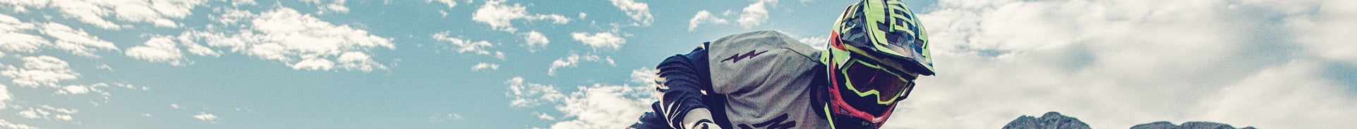 Mountainbiker in Schutzausrüstung und Helm fährt unter blauem Himmel, Modell Haibike NDuro, für Offroad-Abenteuer.