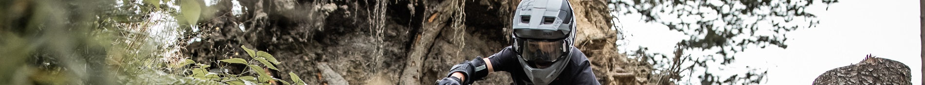 Kind mit Vollvisierhelm und Schutzkleidung beim Mountainbiken im Wald, Teil der Kollektion "kinderhelme".