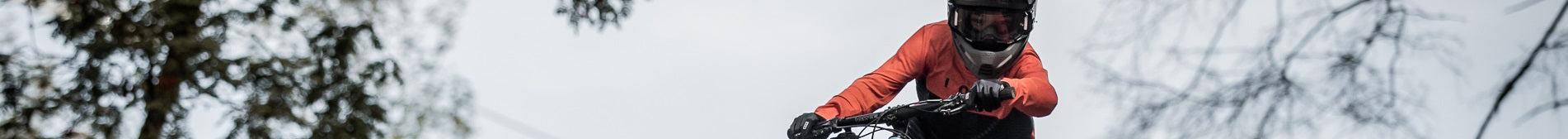 Kind auf E-Bike mit orangener Jacke und Helm fährt im Freien. Ideal für dynamisches Fahren ab 8 Jahren.
