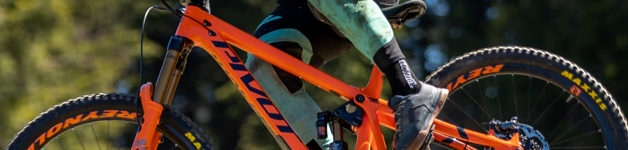 Orange Pivot Mountainbike, voller Fahrt, geeignet für Offroad-Abenteuer, lässige Kleidung des Fahrers.