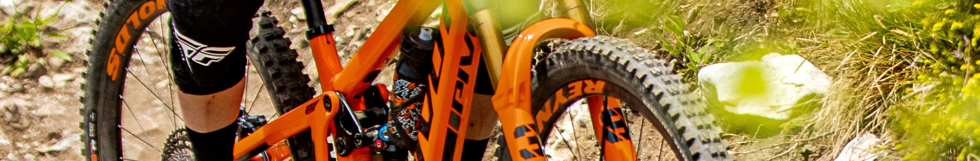 Oranges Pivot Mountainbike auf einem Trail, ideal für Offroad-Abenteuer. Zielgruppe: Mountainbike-Enthusiasten.