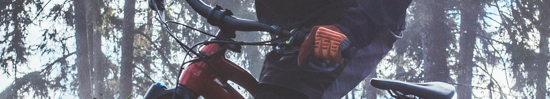 Radfahrer auf rotem Haibike E-MTB Hardtail im Wald, trägt orange Handschuhe. Ideal für Offroad-Abenteuer.