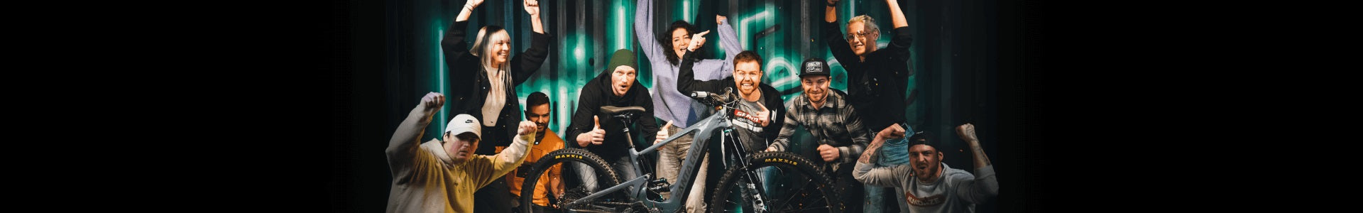 Gruppe jubelt um ein Mountainbike, geeignet für Enthusiasten; Markenname und Modell nicht ersichtlich.