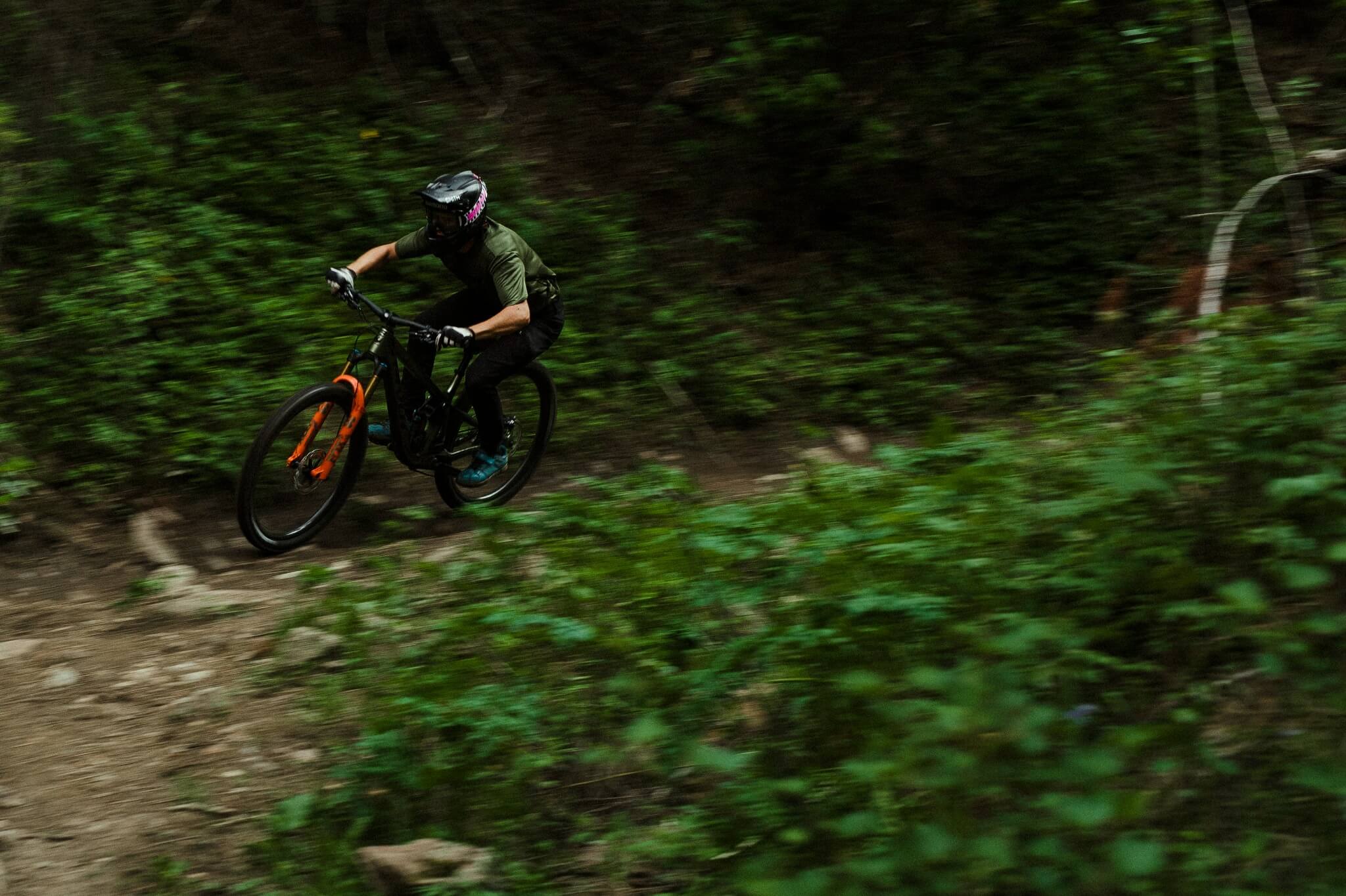 Fahrradfahrer mit Helm auf Mountainbike fährt schnell durch bewaldeten Trail.