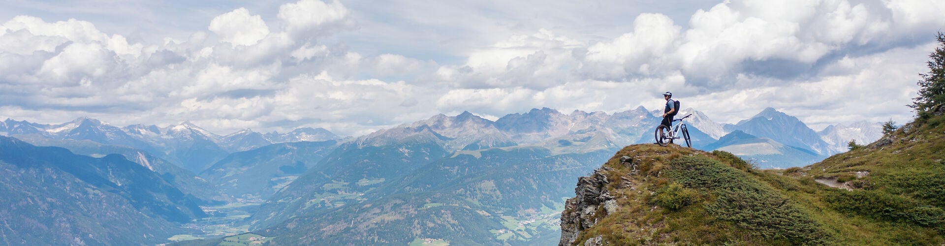 Mountainbiker auf Berggipfel mit Panoramablick; geeignet für Outdoor-Abenteuer. Ideal für Naturliebhaber.
