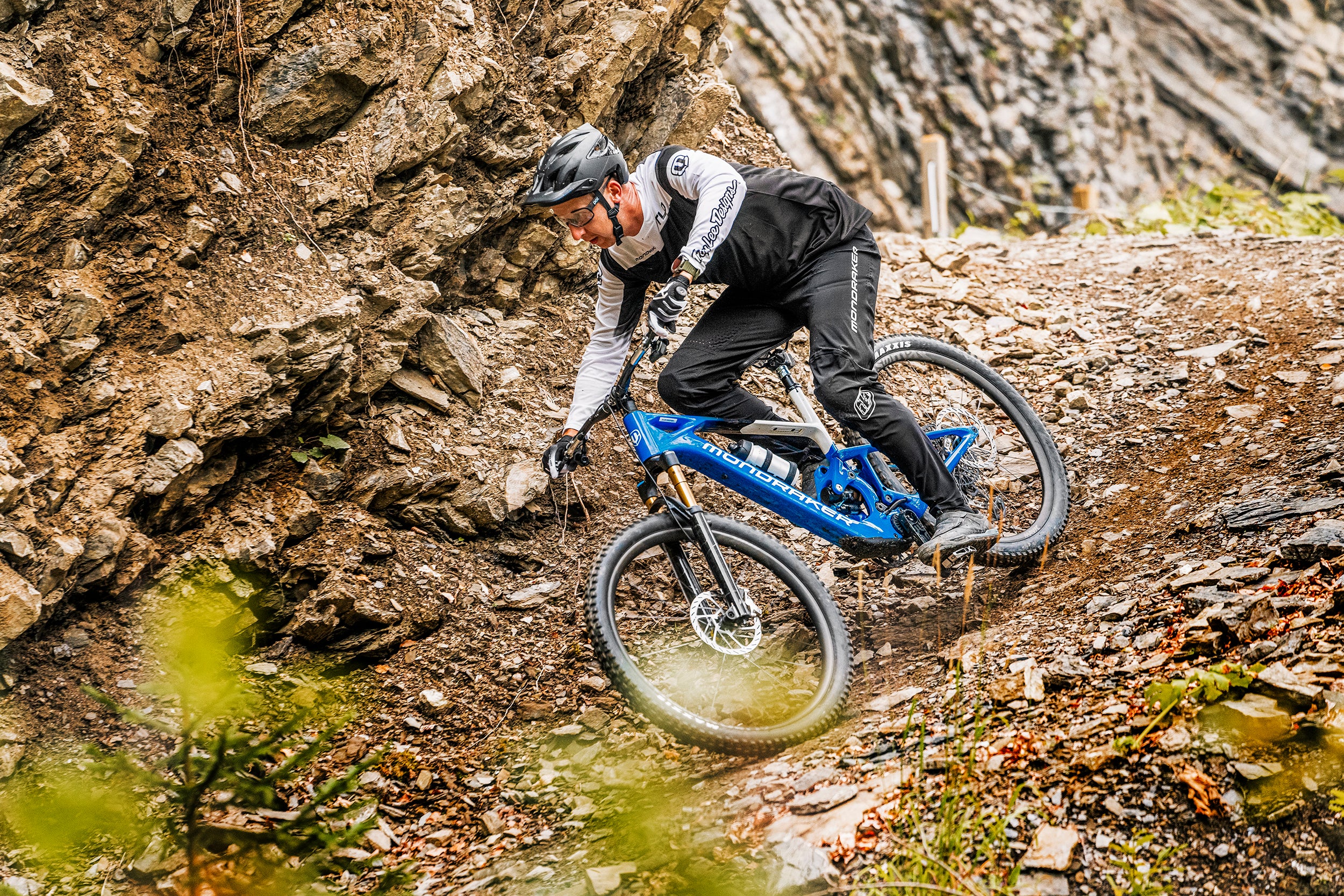Person fährt auf Mondraker Neat E-Mountainbike an einem steinigen Hang entlang.