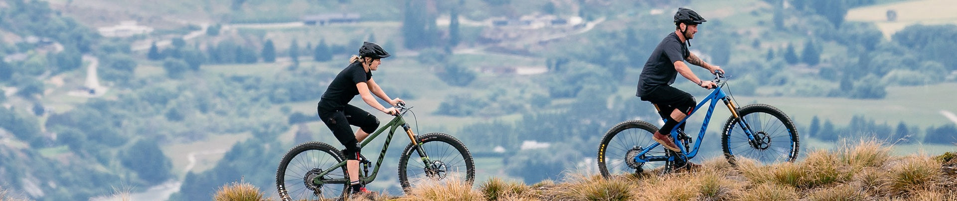 Zwei Personen fahren auf Pivot Mountainbikes durch hügelige Landschaft.