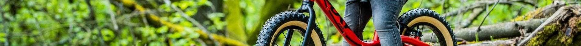 Rotes Kinder-Laufrad im Wald, geeignet für junge Abenteurer, robust mit dicken Reifen für unebene Wege.