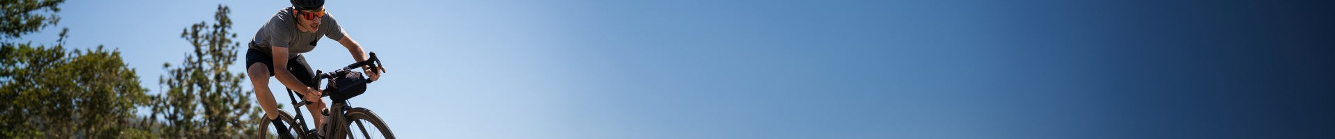 Person auf einem Specialized Diverge Fahrrad fährt auf einer Straße mit blauem Himmel und Bäumen im Hintergrund.
