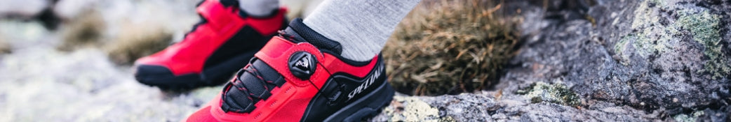 Roter Specialized Fahrradschuh auf steinigem Gelände, ideal für Mountainbiker und Outdoor-Enthusiasten.