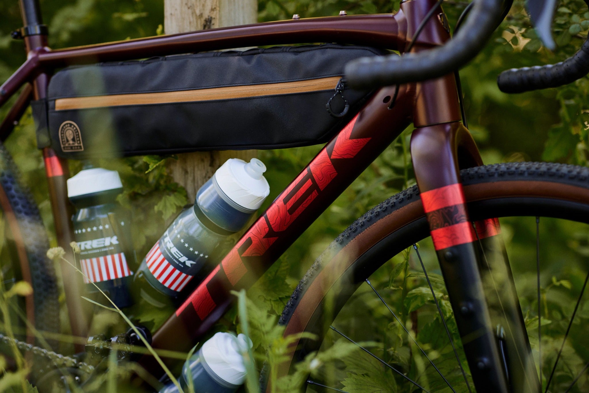 Trek Fahrrad mit Rahmentasche und zwei Trinkflaschen, geeignet für Gravel- und Straßenfahrten in grüner Umgebung.