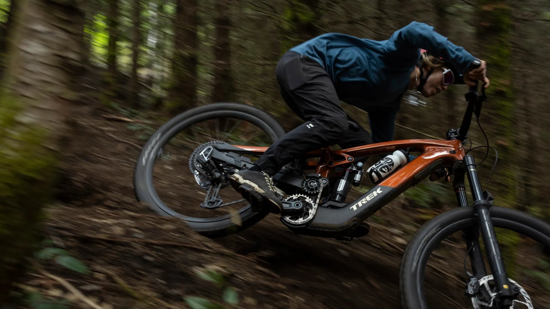Mountainbike Trek Slash Plus in Aktion auf einem Waldweg, Fahrer in Schutzkleidung mit Helm.