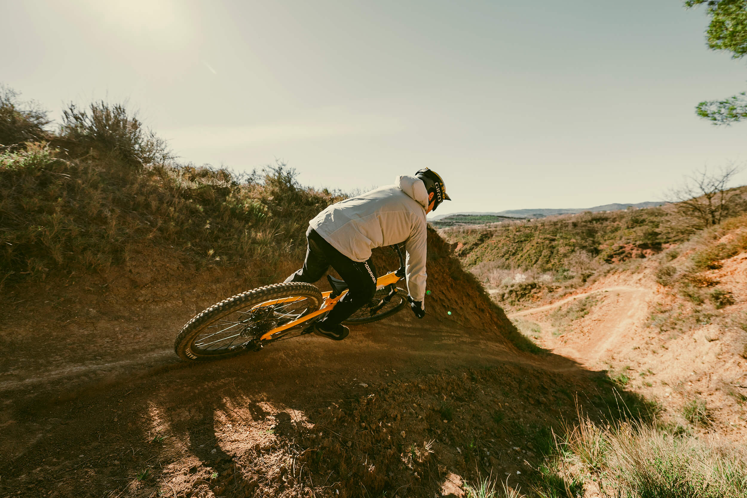 Mountainbiker mit Helm auf einem Mondraker-Mountainbike in Aktion auf einem staubigen, kurvigen Trail.