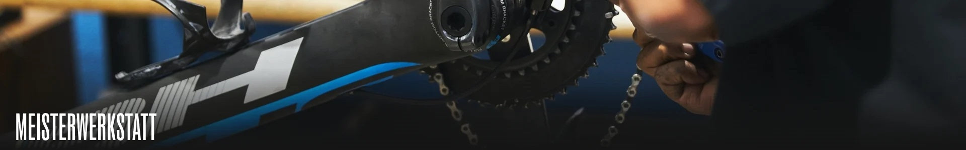 Fahrrad wird in einer Werkstatt gewartet, handgeführtes Werkzeug justiert den Antrieb. Marke Meisterwerkstatt.