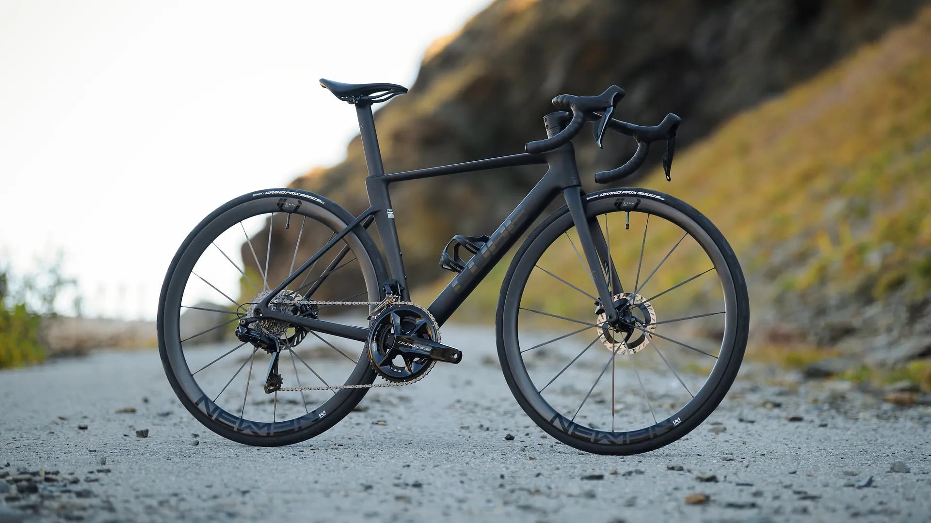 Schwarzes Rennrad auf Schotterweg, geeignet für sportliche Fahrer, mit Scheibenbremsen und aerodynamischem Rahmen.