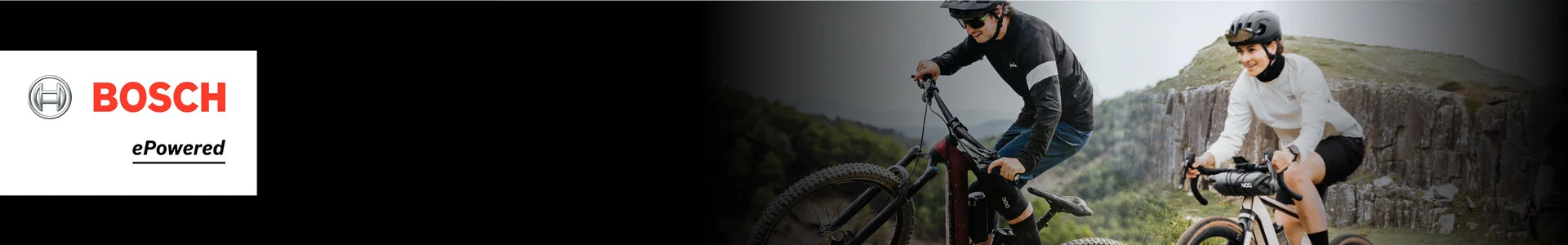 Zwei Personen fahren mit Bosch E-Mountainbikes in hügeligem Gelände. Links ist das Bosch-Logo mit "ePowered" sichtbar.