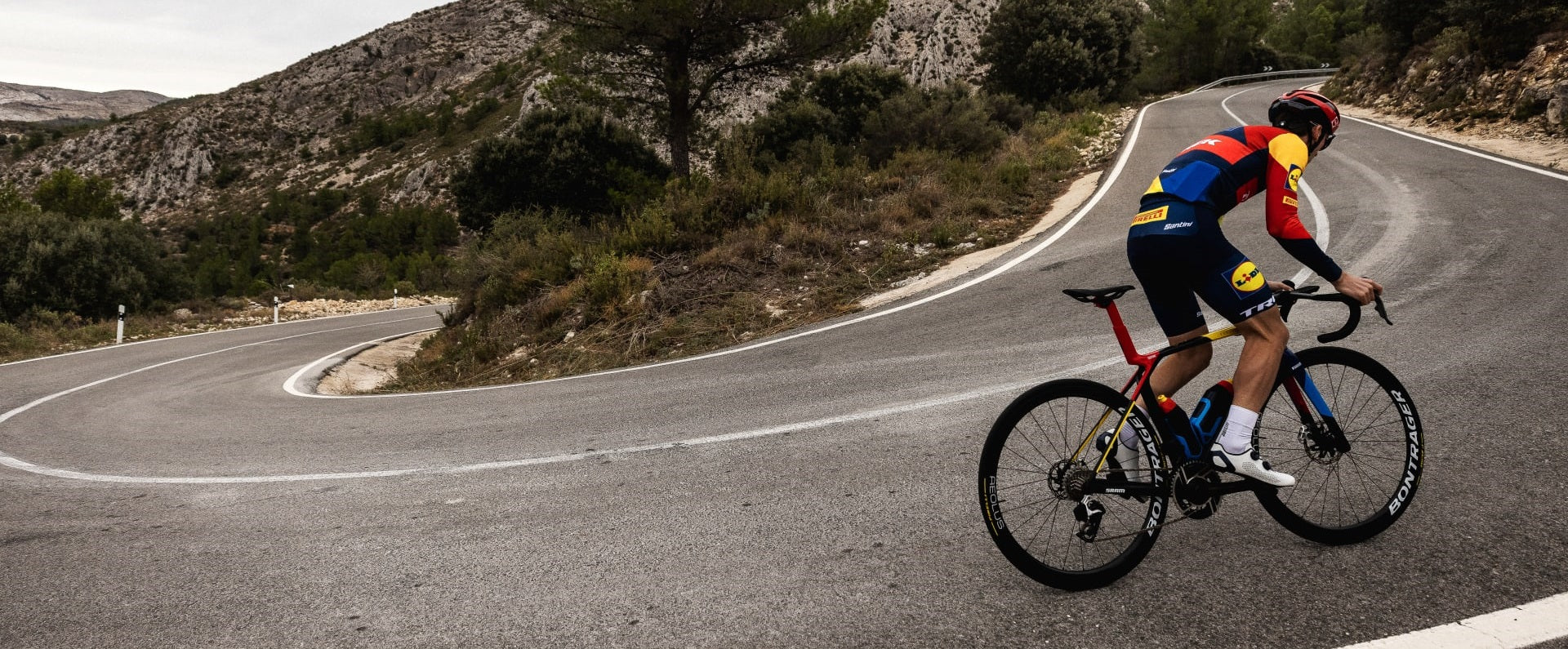 Radfahrer auf einer Bergstraße mit Trek Madone Fahrrad und Bontrager Rädern. Geeignet für Sportenthusiasten.