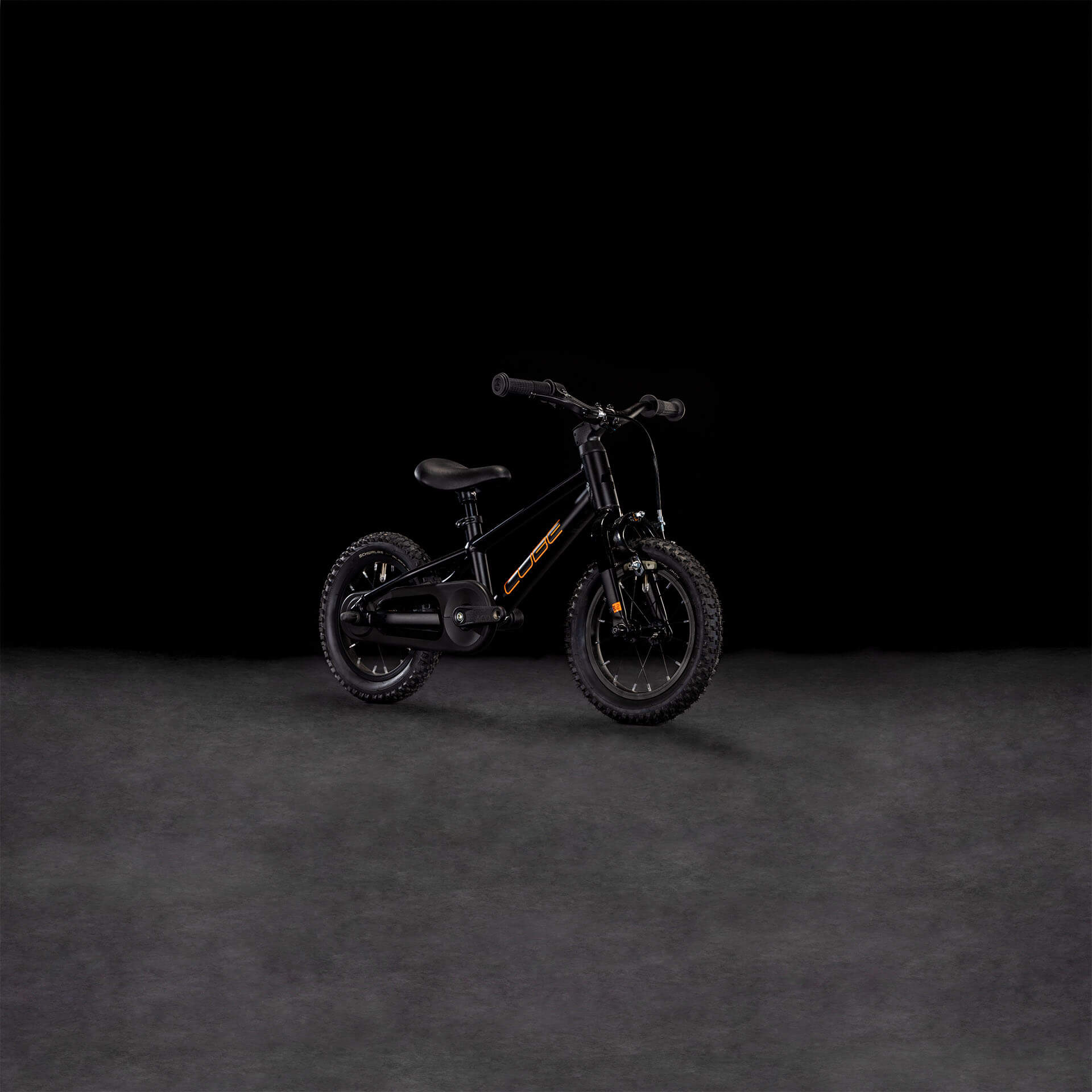 Schwarzes Kinderfahrrad Cube NuMove mit dickem Reifenprofil, ideal für junge Fahranfänger, auf dunklem Hintergrund.