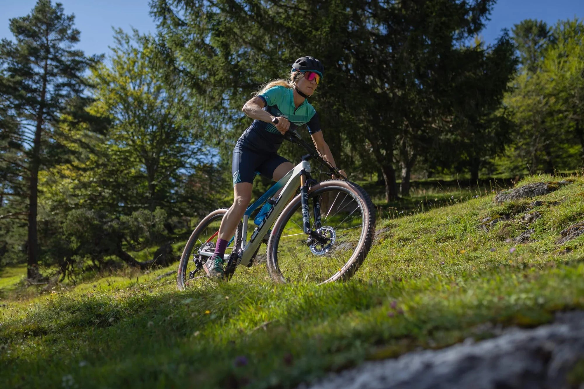 Mountainbikerin auf Cube Hardtail fährt steilen Waldpfad hinab, ideal für sportliche Outdoor-Aktivitäten.