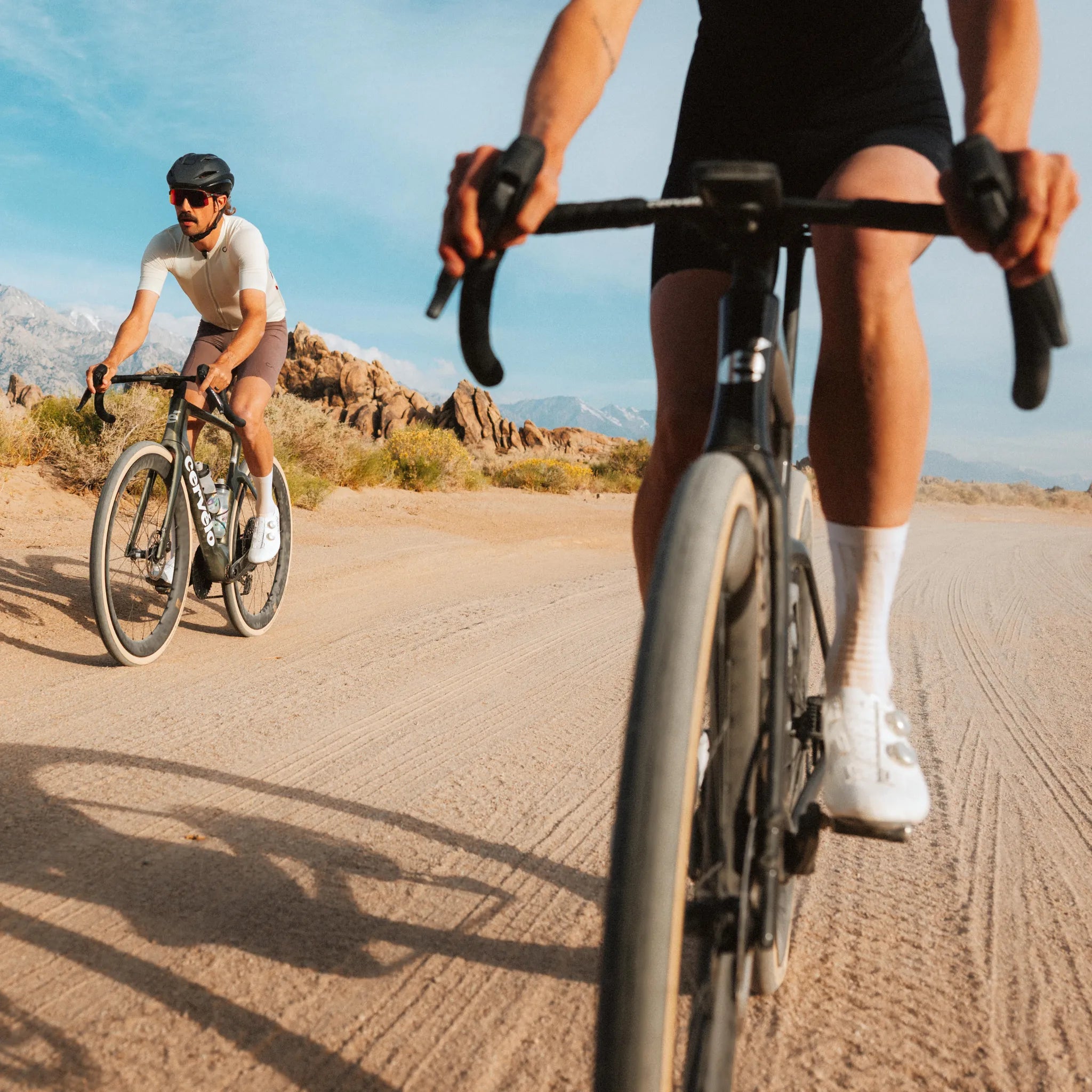 Zwei Radfahrer auf Cervelo Aspero 5 auf einer staubigen Straße in einer Wüstenlandschaft. Tätig bei sonnigem Wetter.
