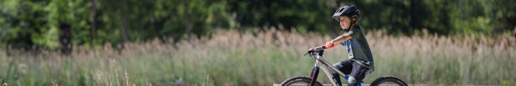 Kind mit Helm fährt Fahrrad im Freien; ideal für Kinder, keine Markenangaben erkennbar.