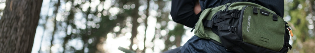 Grüne CUBE-Hüfttasche, outdoor-tauglich, getragen von einer Person im Wald, ideal für Wanderungen und Radtouren.