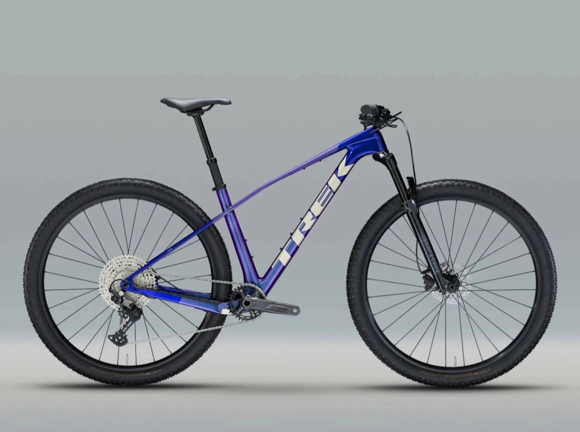 Trek Mountainbike mit blau-violettem Rahmen, Scheibenbremsen und breiten Reifen, ideal für Geländefahrten.
