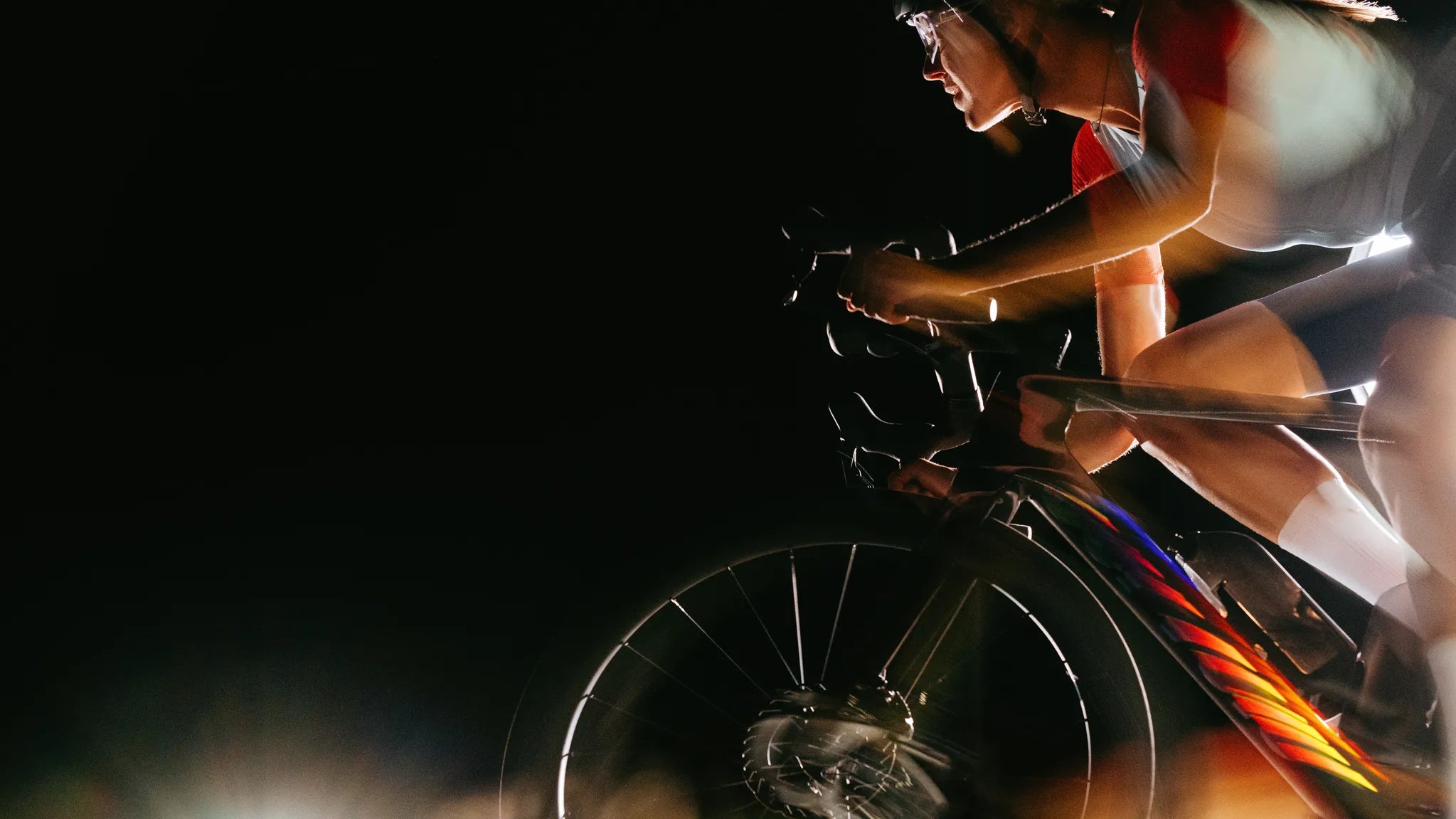 Rennradfahrer in rasanter Fahrt bei Nacht mit hochwertigem Rennrad und Sportbekleidung.