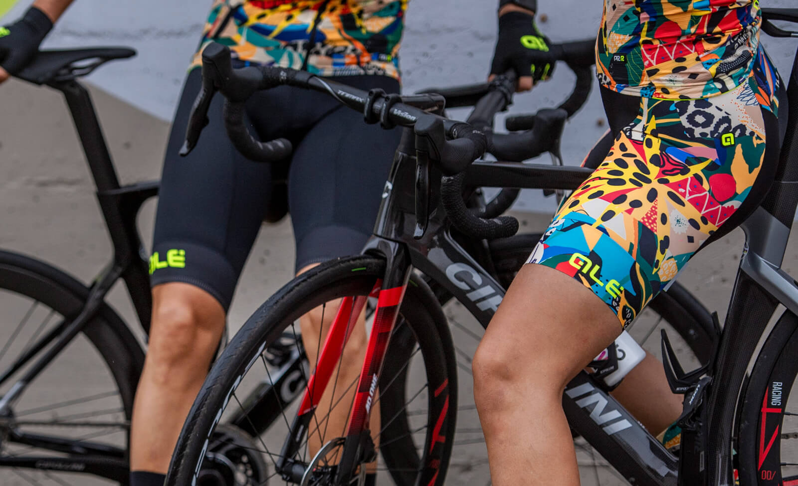 Radsportbekleidung von Alé mit buntem Muster, getragen von Radfahrern auf schwarzen Rennrädern.