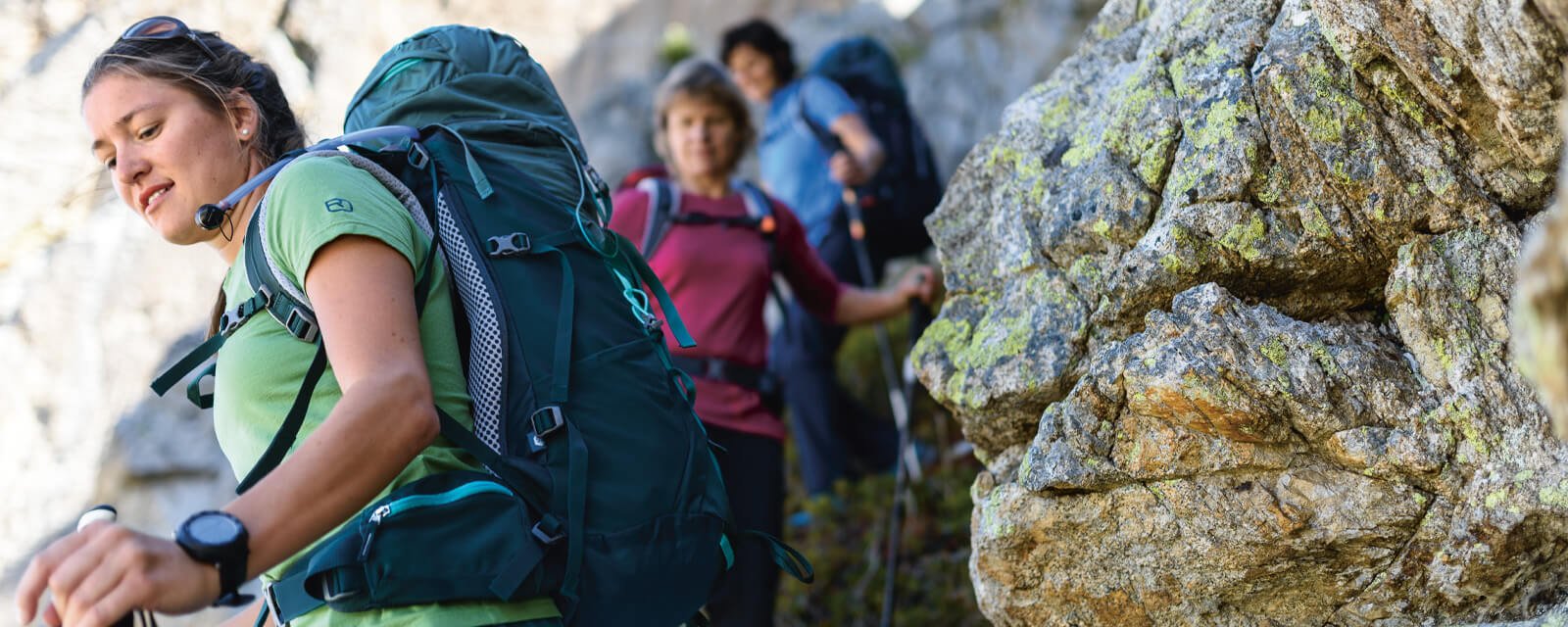 Gruppe von Wanderern in den Bergen mit Deuter-Rucksäcken, unterwegs auf felsigem Pfad.