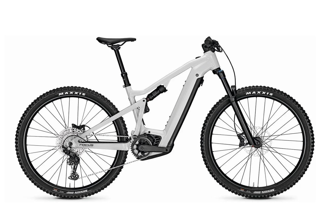 Weißes Focus E-Mountainbike mit vollem Federweg, Maxxis-Reifen und Shimano-Schaltung, ideal für Geländefahrten.