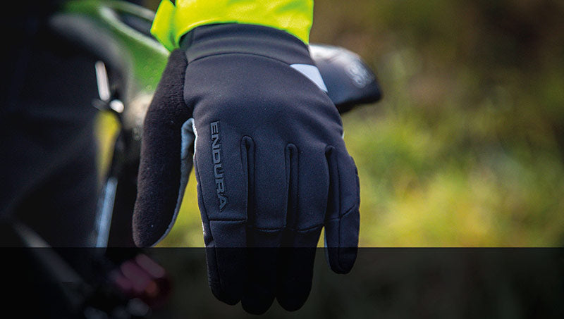 Schwarzer Endura-Handschuh für Radfahrer im Regen, mit Reflektorstreifen und grünem Hintergrund.