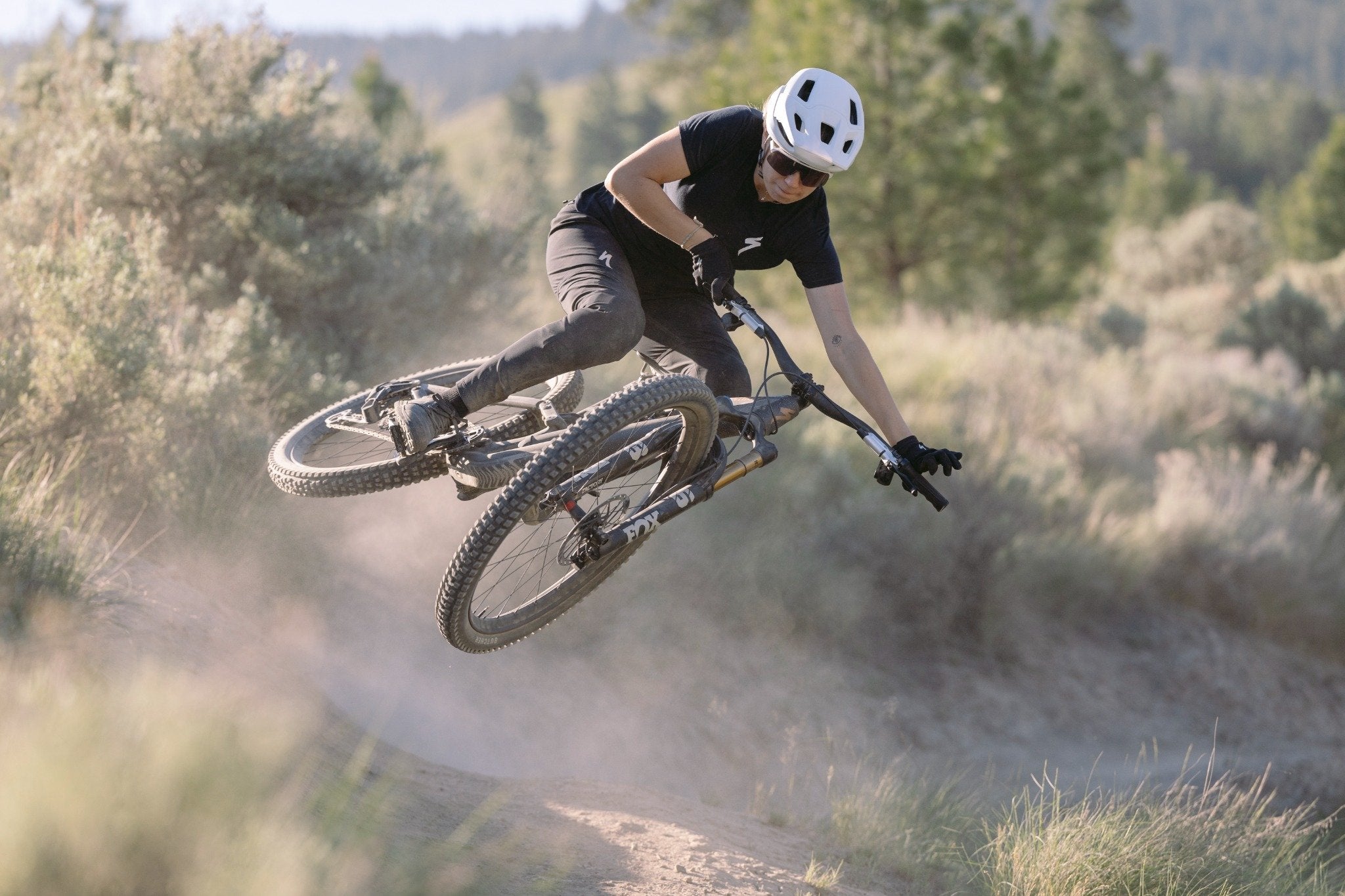Fahrradfahrer auf einem Mountainbike-Sprung im Gelände, trägt Helm und Schutzkleidung; geeignet für Offroad-Enthusiasten.