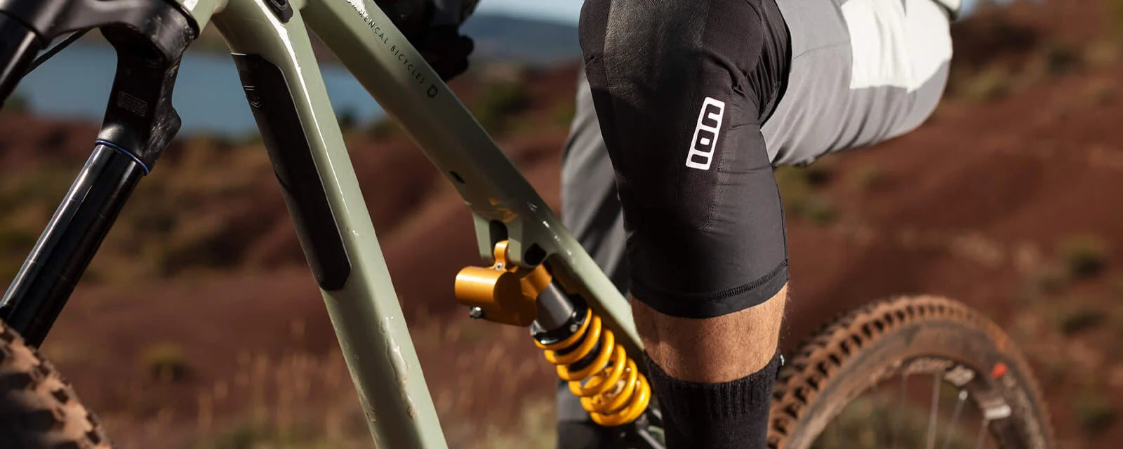 Mountainbike mit ION-Knieschoner in Outdoor-Umgebung, Fokus auf Federung und Schutzkleidung. Ideal für Mountainbiker.
