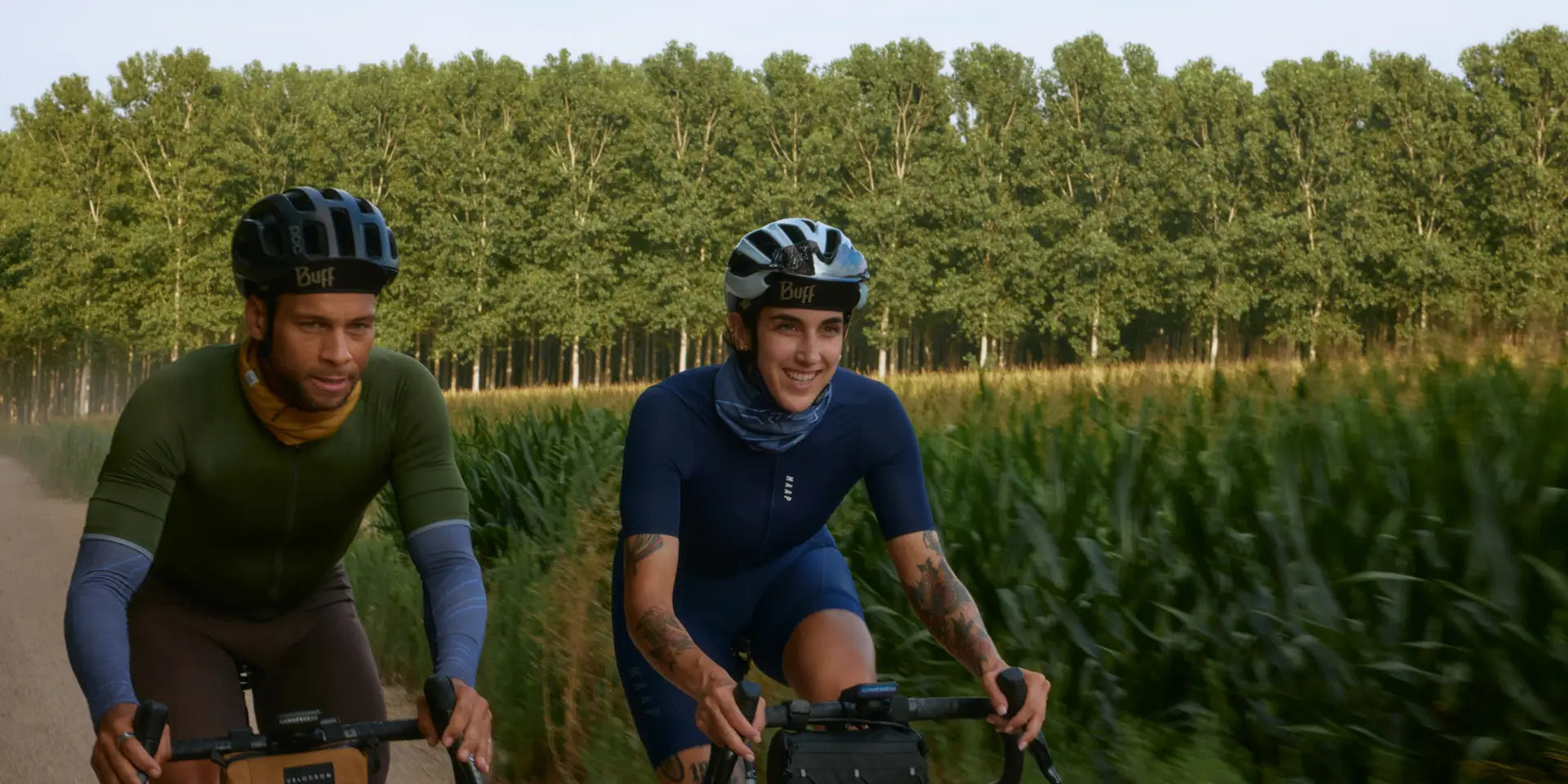 Zwei Radfahrer mit Buff-Helmen und -Tüchern auf einem Waldweg, ideal für Outdoor-Enthusiasten.