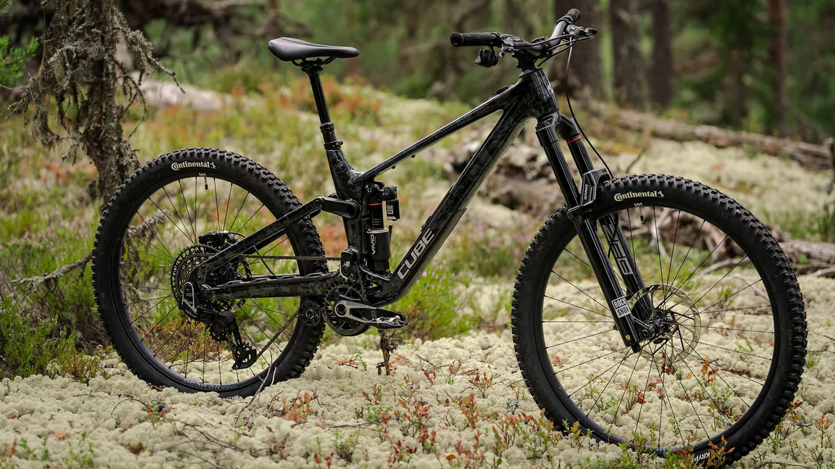 Schwarzes Cube FRITZZ C:62 SUPER TM
 im Wald auf moosigem Boden, ideal für Offroad-Abenteuer, zeigt robuste Reifen und Federung.