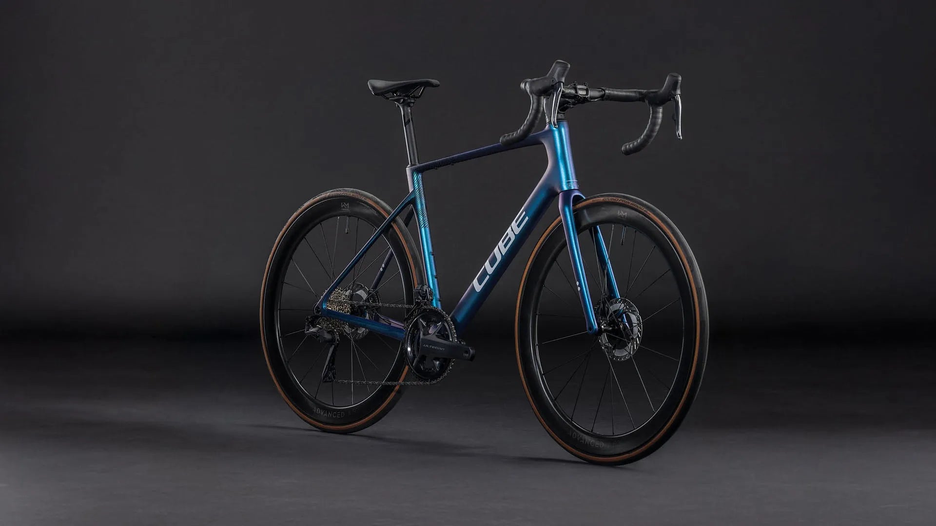 Blaues Cube Attain C:62 SLT Rennrad mit Carbonrahmen und Scheibenbremsen auf dunklem Hintergrund, für Sportenthusiasten und Radfahrer.