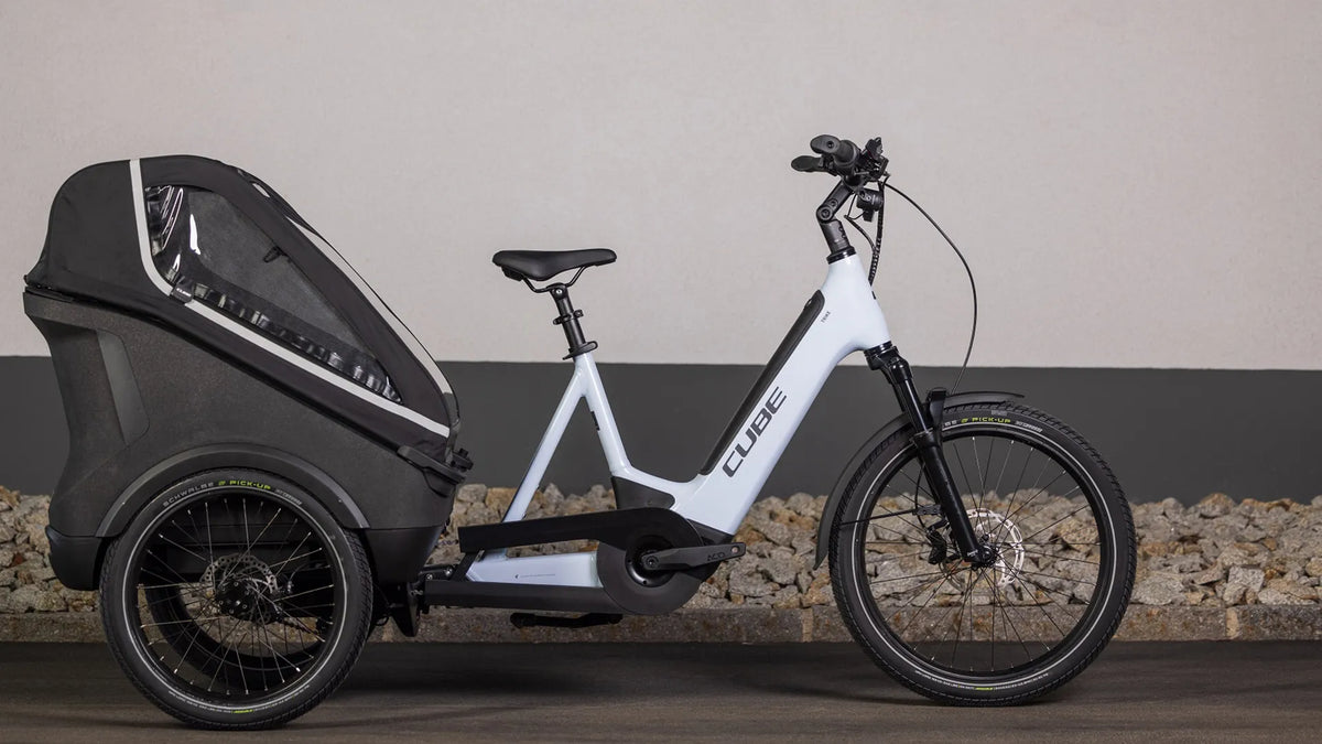 Weißes CUBE TRIKE FAMILY HYBRID 750 mit großem schwarzen Transportanhänger, ideal für urbanen Transport und Familien.